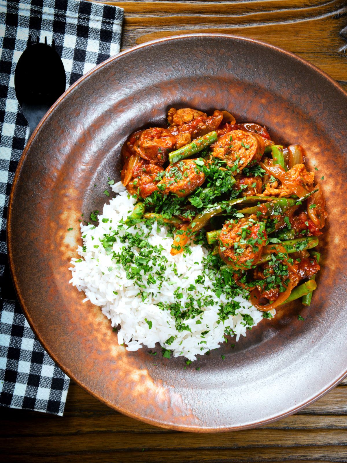Overhead Indian beef & pork sausage curry with green beans served with plain rice.
