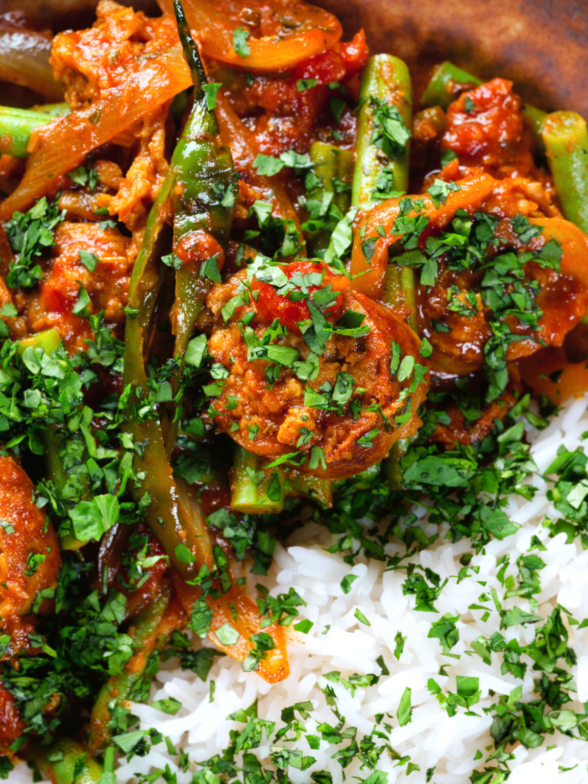 Close-up overhead Indian beef & pork sausage curry with green beans served with plain rice.