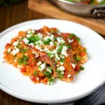 Baked pork chops with tomato orzo, feta cheese and parsley.