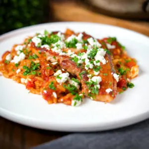 One-pot baked pork chops with tomato orzo, feta cheese and parsley.