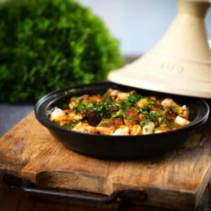Harissa halloumi tagine with almonds in a traditional cooking pot.