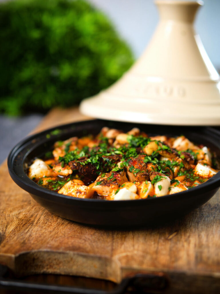Harissa halloumi tagine with almonds in a traditional cooking pot.