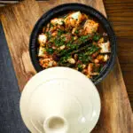 Overhead harissa halloumi tagine with almonds in a traditional cooking pot.