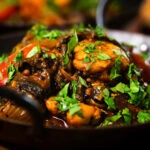 Close-up Indian-influenced chicken, mushroom and tomato curry served in a karai.
