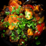 Overhead close-up Indian-influenced chicken, mushroom and tomato curry served in a karai.