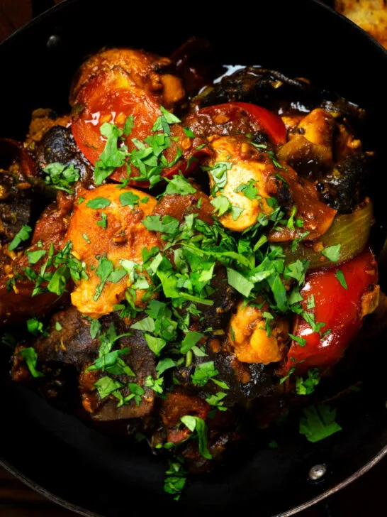 Overhead close-up Indian-influenced chicken, mushroom and tomato curry served in a karai.