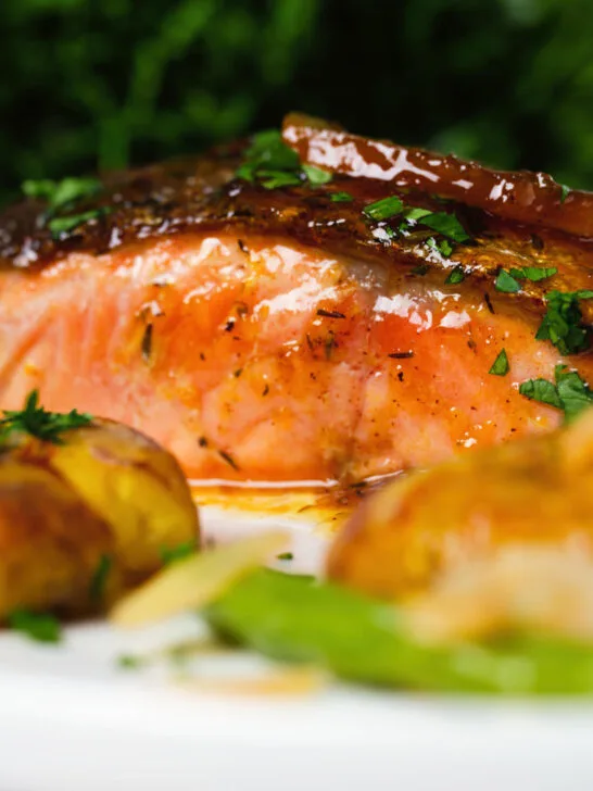 Close-up orange and marmalade glazed salmon with new potatoes and green beans.
