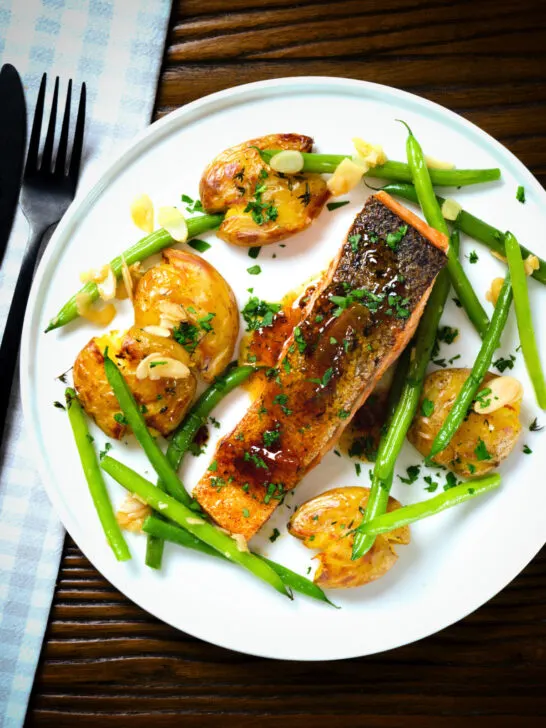 Overhead orange and marmalade glazed salmon with new potatoes and green beans.