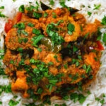 Overhead close-up Andhra style chicken curry (kodi kura) served with basmati rice.