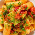 Close-up overhead chorizo sausage and bacon pasta in a tomato sauce.