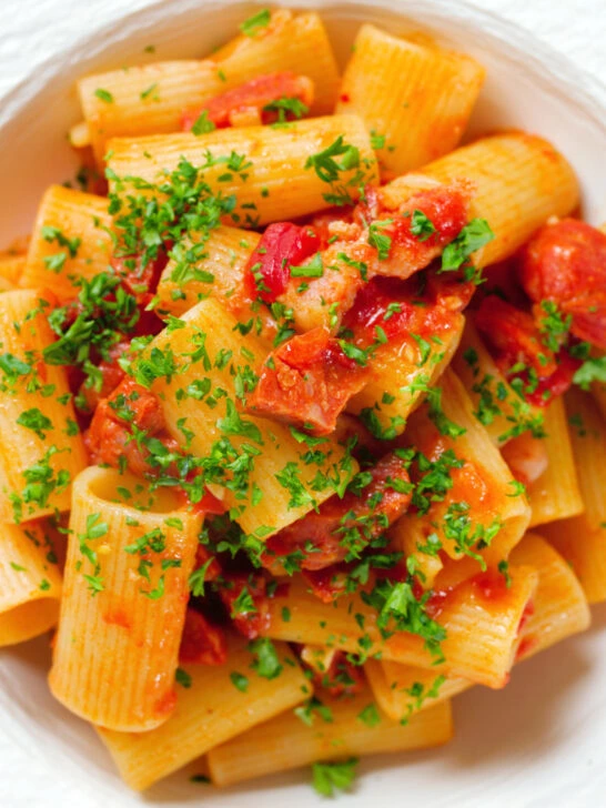 Close-up overhead chorizo sausage and bacon pasta in a tomato sauce.