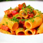 Close-up chorizo sausage and bacon pasta in a tomato sauce.