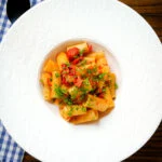 Overhead chorizo sausage and bacon pasta in a tomato sauce.