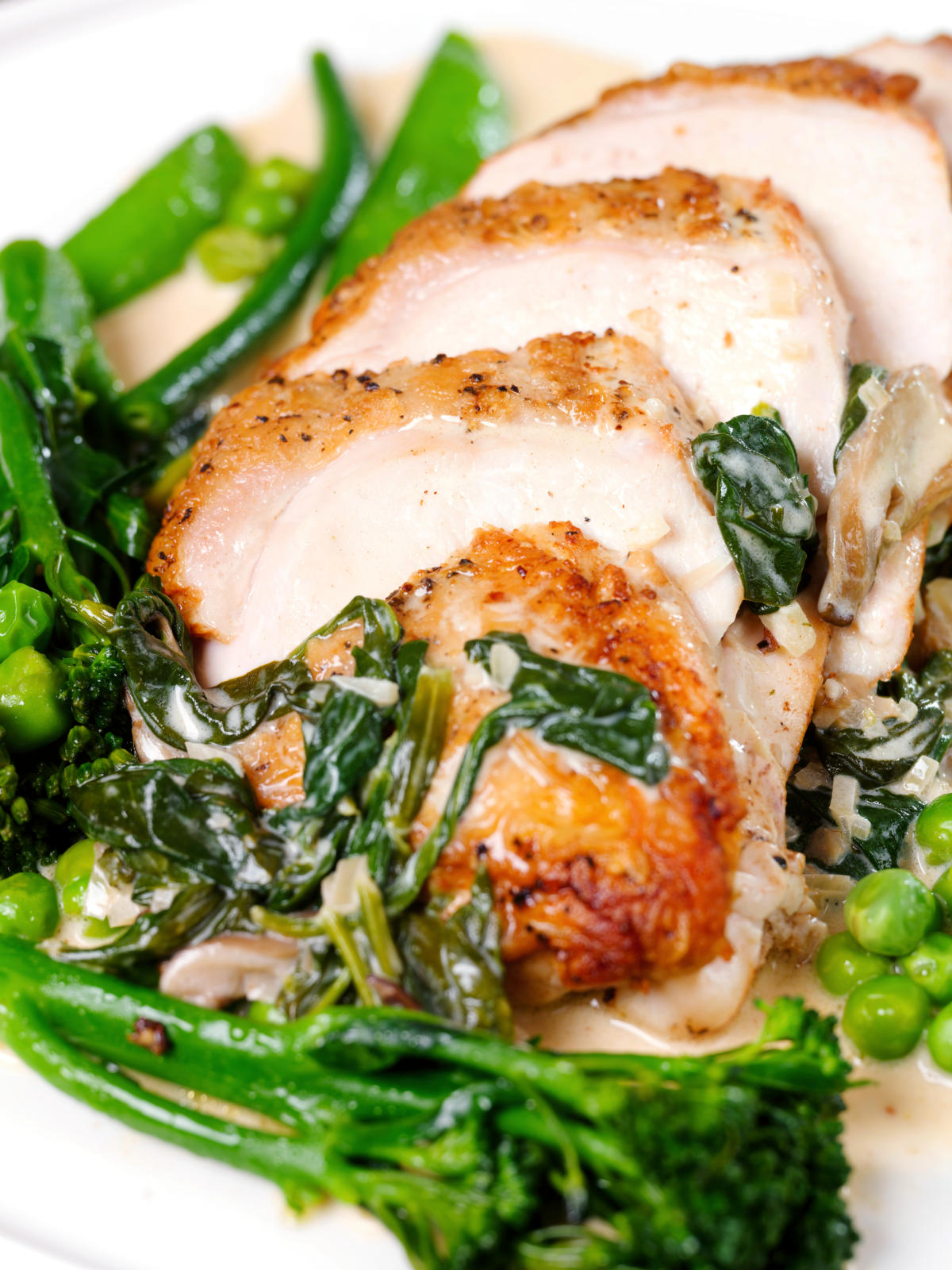Close-up creamy chicken and oyster mushroom Florentine served with green vegetables.