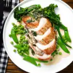 Overhead creamy chicken and oyster mushroom Florentine served with green vegetables.