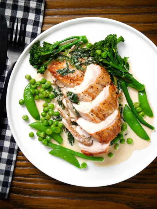 Overhead creamy chicken and oyster mushroom Florentine served with green vegetables.