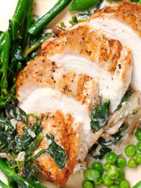 Overhead close-up creamy chicken and oyster mushroom Florentine served with green vegetables.