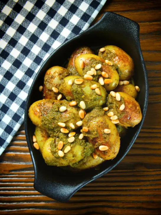 Overhead brown butter and basil pesto potatoes garnished with pine nuts.
