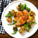 Overhead roasted chicken legs with lemon and thyme served with pesto potatoes and broccoli.