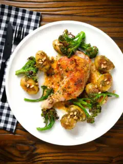 Overhead roasted chicken legs with lemon and thyme served with pesto potatoes and broccoli.