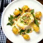 Overhead roasted halibut with a potted shrimp and vermouth sauce, new potatoes and runner beans.