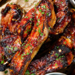 Close-up overhead sticky BBQ sauce glazed lamb spare ribs served with pickles.