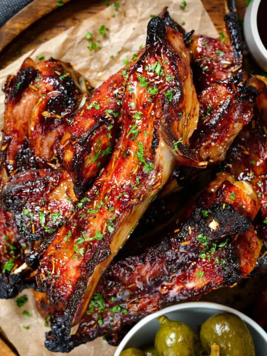 Close-up overhead sticky BBQ sauce glazed lamb spare ribs served with pickles.