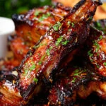 Close-up sticky BBQ sauce glazed lamb spare ribs served with potato wedges.