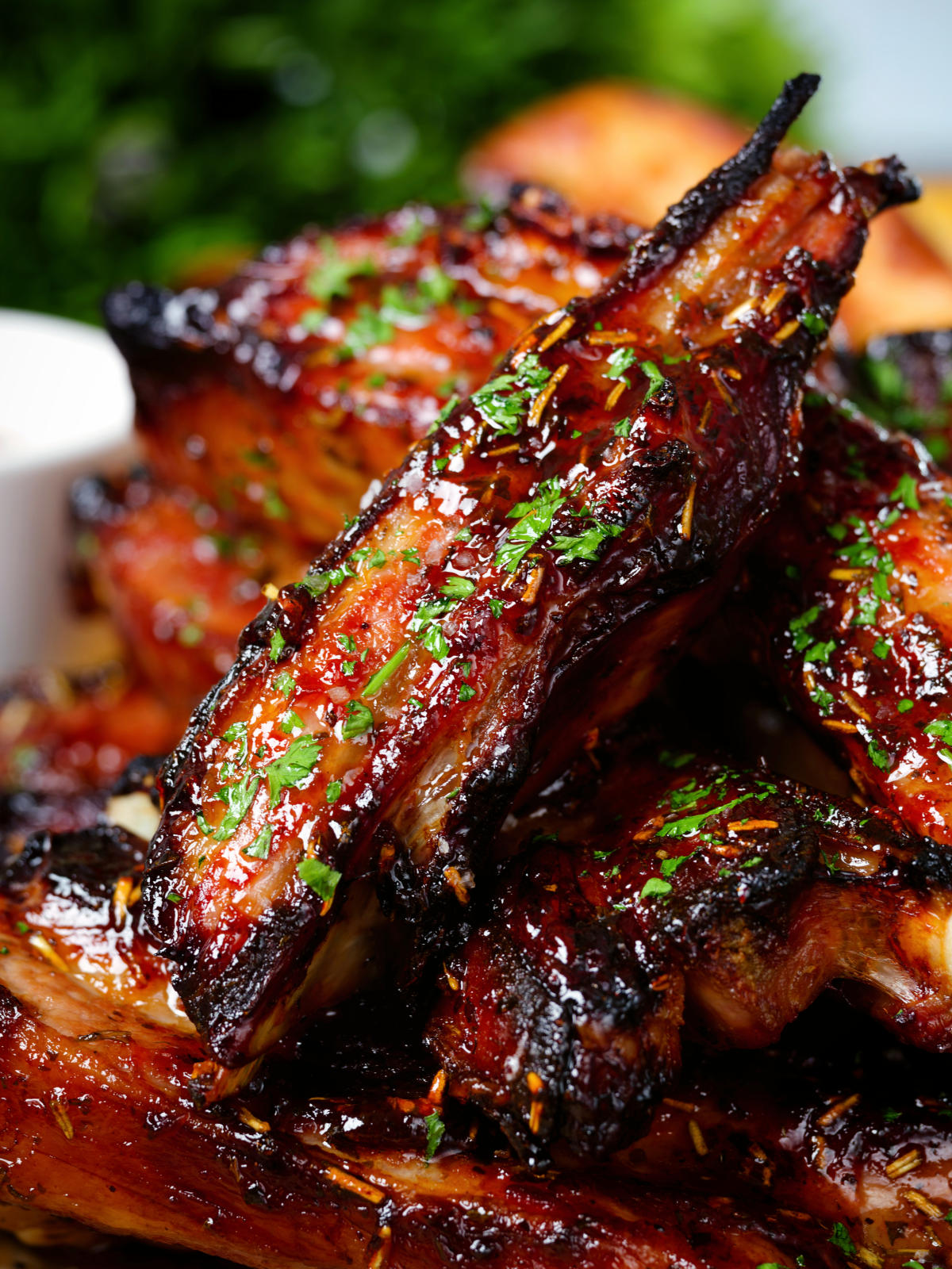 Close-up sticky BBQ sauce glazed lamb spare ribs served with potato wedges.