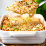 Cheesy chicken, bacon and potato gratin being served with a spoon.