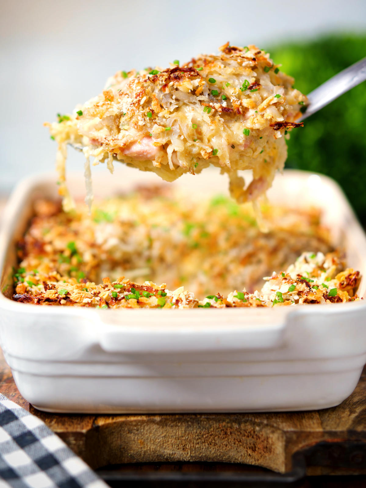 Cheesy chicken, bacon and potato gratin being served with a spoon.