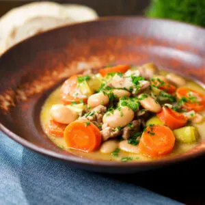 Mustardy chicken and butterbean stew with leeks and carrots served with bread.