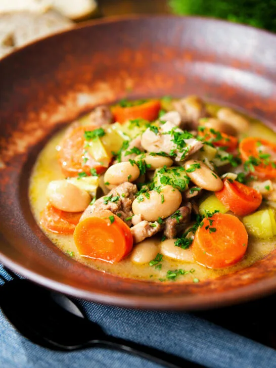 Chicken and butterbean stew with leeks and carrots served with bread.