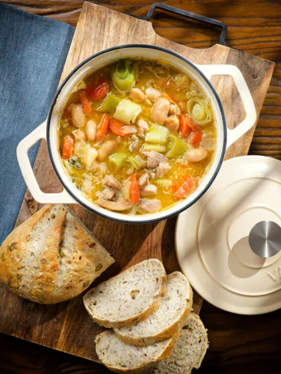 Overhead chicken and butterbean stew with leeks and carrots served in a cooking pot.