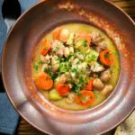 Overhead chicken and butterbean stew with leeks and carrots served with bread.