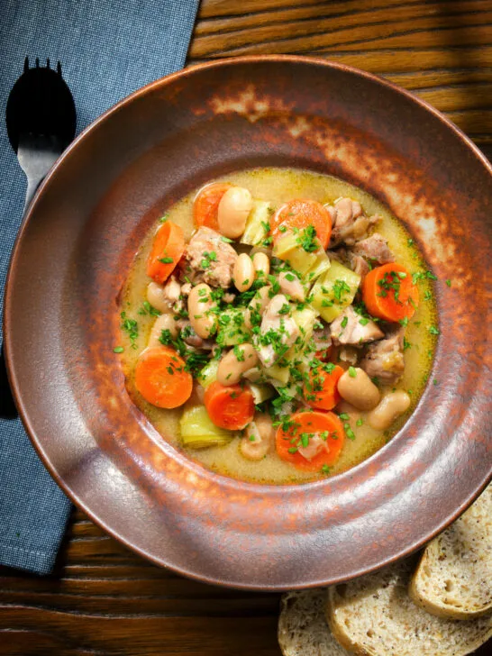 Overhead chicken and butterbean stew with leeks and carrots served with bread.