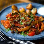 Curried pork chops with tomatoes and raisins served with aloo jeera and raita.