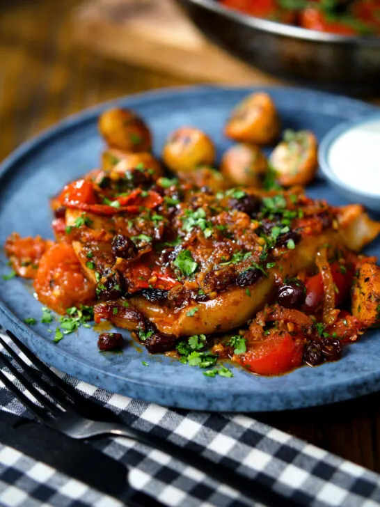 Curried pork chops with tomatoes and raisins served with aloo jeera and raita.