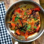 Overhead curried pork chops with tomatoes, onions and raisins.