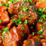 Close-up Filipino beef mechado stew with carrots and potatoes in a tomato sauce.