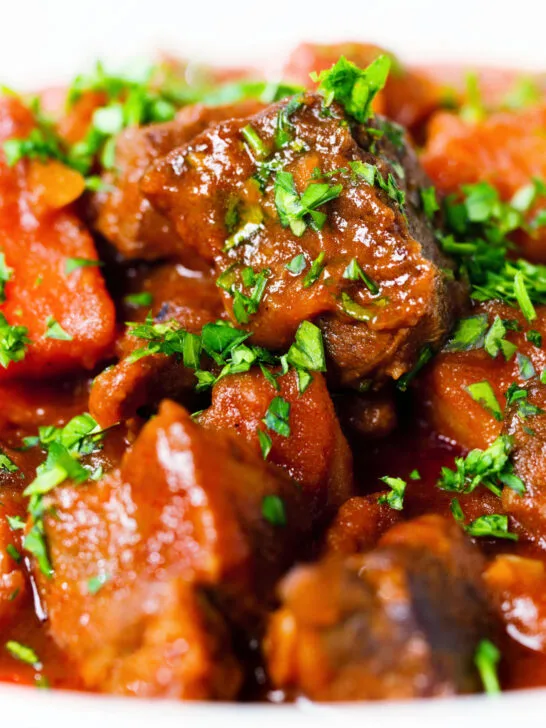 Close-up Filipino beef mechado stew with carrots and potatoes in a tomato sauce.