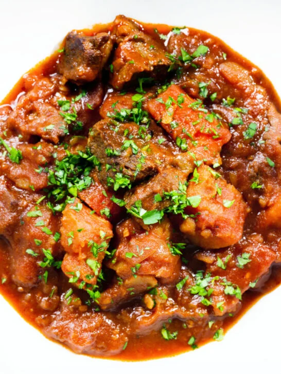 Close-up overhead Filipino beef mechado stew with carrots and potatoes in a tomato sauce.