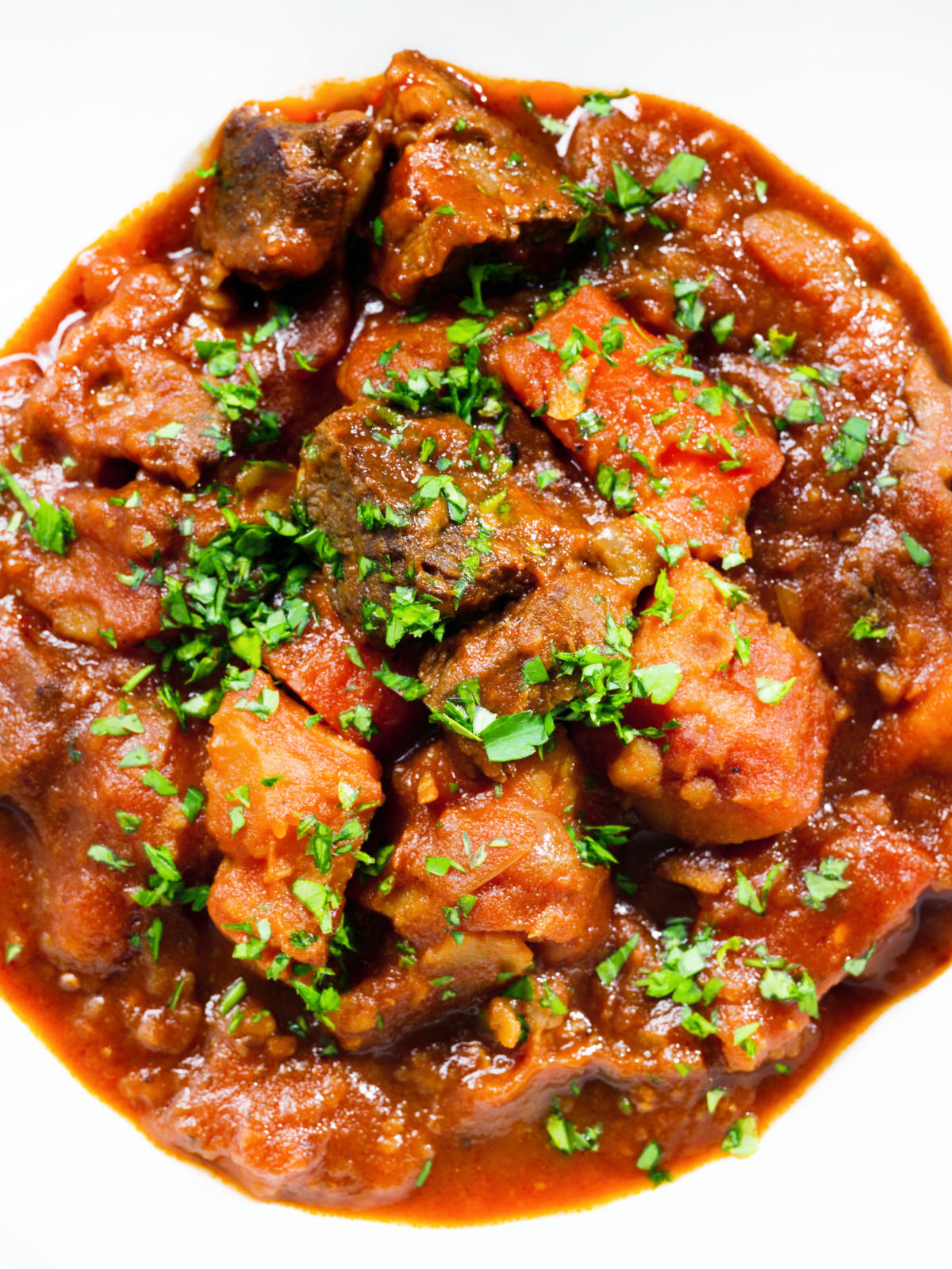 Close-up overhead Filipino beef mechado stew with carrots and potatoes in a tomato sauce.