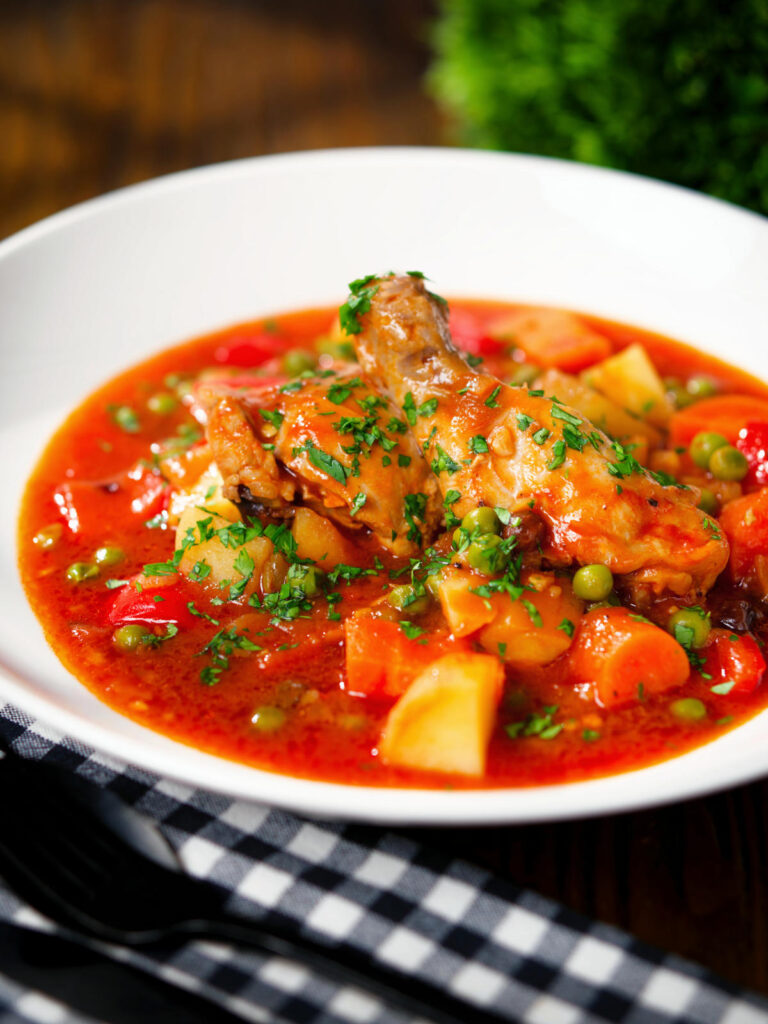 Filipino chicken afritada stew with potatoes, carrots, peppers and peas.