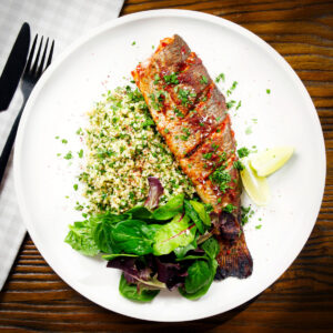Harissa baked rainbow trout with herbed bulgur wheat, side salad and lime wedges.