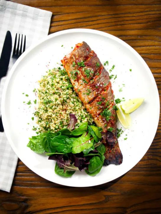 Overhead harissa baked/roasted rainbow trout with herbed bulgur wheat.