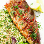 Overhead close-up harissa baked/roasted rainbow trout with herbed bulgur wheat.