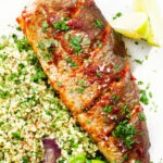 Overhead close-up harissa baked/roasted rainbow trout with herbed bulgur wheat.