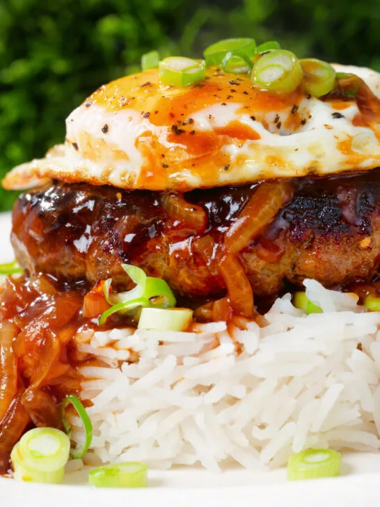 Close-up Hawaiian loco moco: beef patty, white rice, gravy and a fried egg.