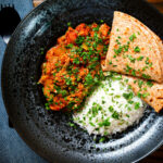 Overhead Indian-influenced canned tuna curry served with rice and chapatis.